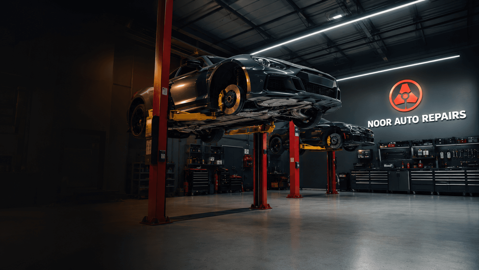 Technician inspecting a car's engine bay on a hydraulic lift at Noor Auto Repairs